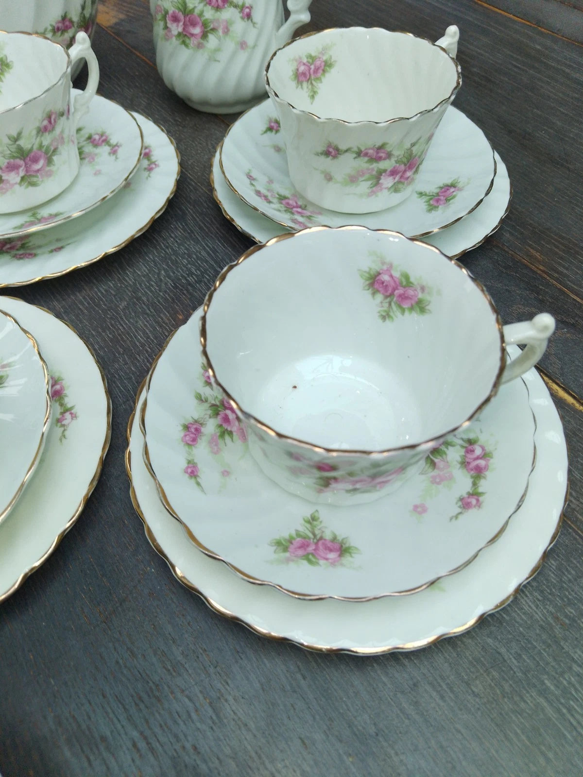 Antique pink rose tea set with delicate floral patterns and gold trim on cups and saucers