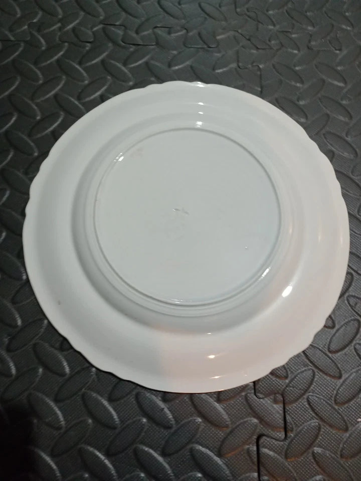 Back view of a white Copeland Spode Imari dinner plate resting on a patterned surface