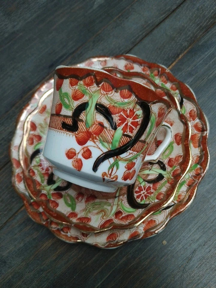 Antique Imari tea trio with intricate red and green floral patterns on a wooden surface