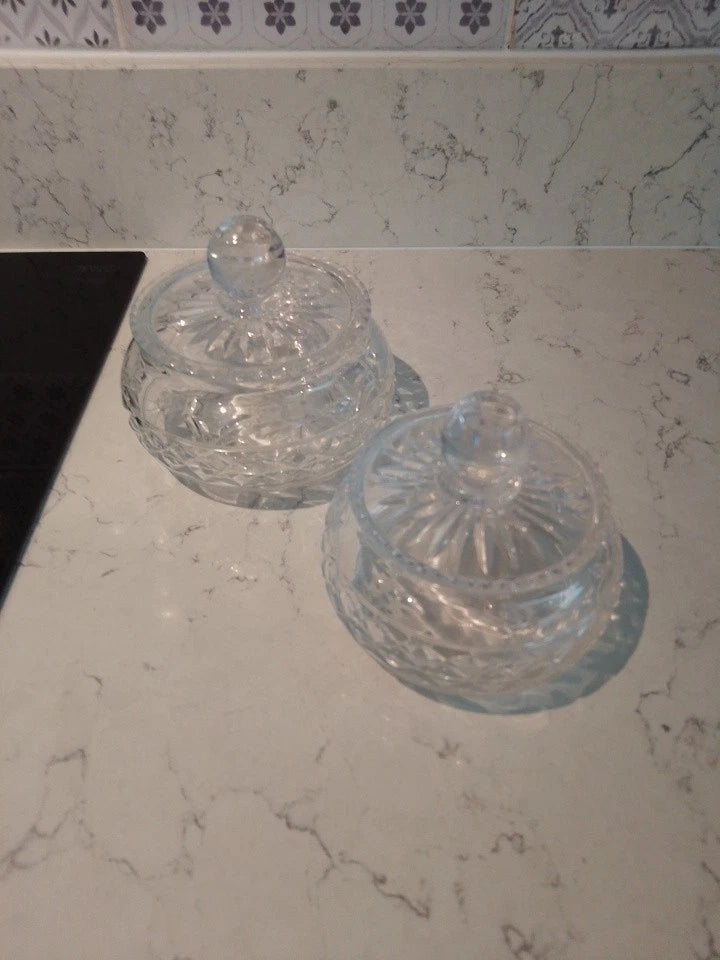 Pair of vintage Stuart crystal jars with decorative lids on a marble surface