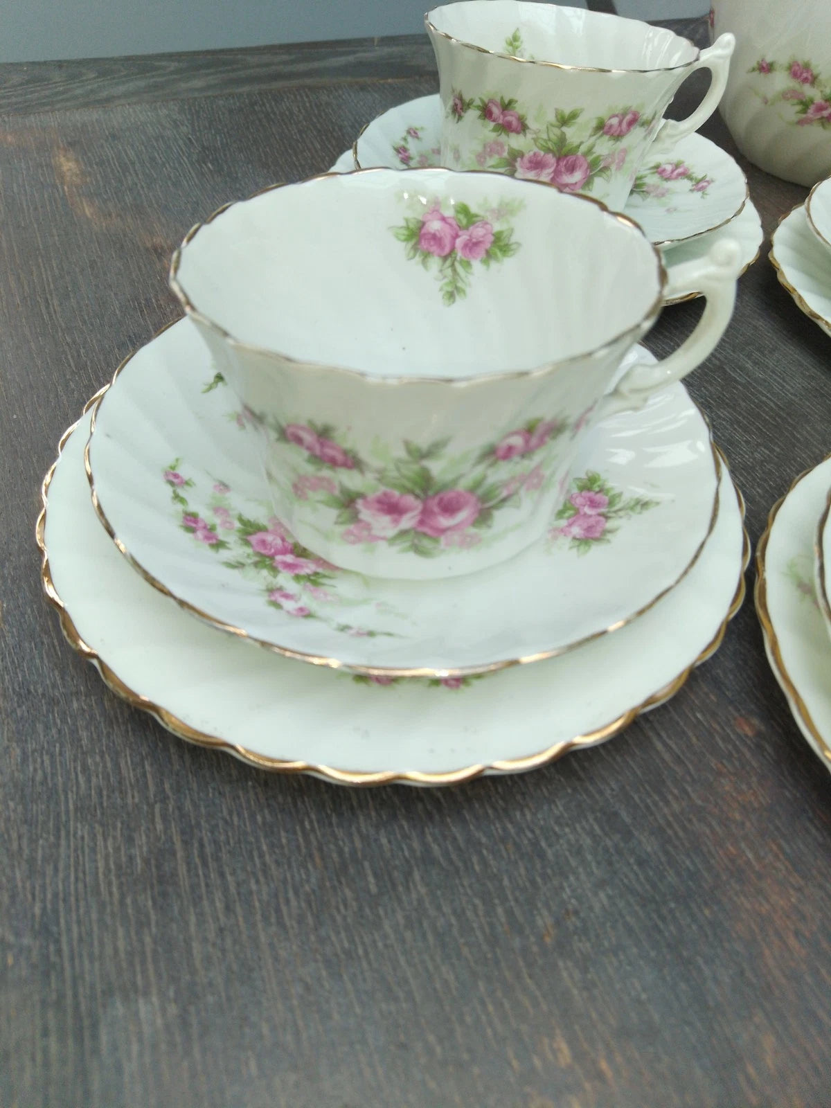 Antique pink rose tea set with floral china cups and saucers featuring gold-rimmed edges