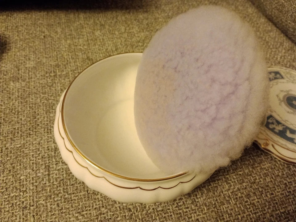Coalport Revelry powder box with gold trim and fluffy powder puff on textured fabric background