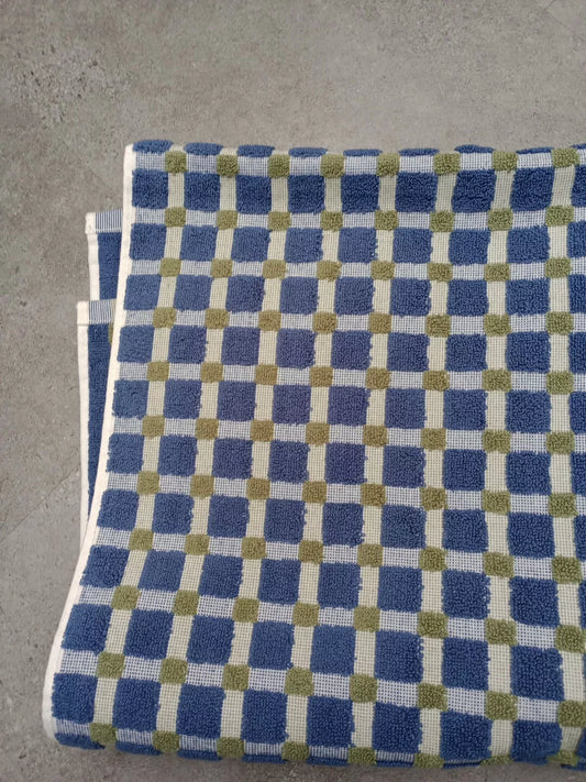 Blue and green checkered DKNY bath towel folded on a grey surface